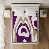 Shai Animal Print Cotton Throw Blanket in Purple and Beige, on a bed