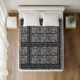 Thora Tribal Cotton Throw Blanket in Black, on a bed