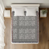 Thora Tribal Cotton Throw Blanket in Gray, on a bed