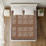 Thora Tribal Cotton Throw Blanket in Rust Brown, on a bed