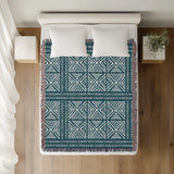 Thora Tribal Cotton Throw Blanket in Teal, on a bed