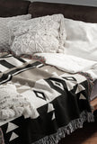Fika Southwestern Cotton Blend Blanket Throw in Beige, Black and Off-White, draped over a chair