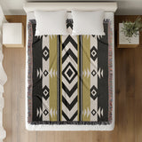 Fika Southwestern Cotton Blend Blanket Throw in Black and Dull Gold, on a bed