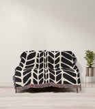 Freda Hand Woven Throw Blanket in Black and Beige, draped over a sofa