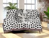 Inky Leopard Cotton Blend Blanket Throw in Black and Off-White, draped over a chair