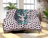 Inky Leopard Cotton Blend Blanket Throw in Teal, Purple and Off-White, draped over a chair