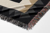 Kotu Snake Cotton Blend Blanket Throw in Black, Beige and Gray, draped over a chair