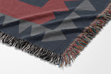 Kotu Snake Cotton Blend Blanket Throw in Red, Green and Blue Gray, draped over a chair