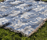 Leonard Tiger Cotton Blend Blanket Throw in Light Blue and Off-White, draped over a chair