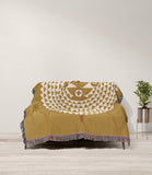Mossi African Mask 100% Cotton Blanket in Gold and Beige, draped over a sofa
