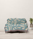 Nami Abstract Floral Blanket Throw in Blue and Beige, draped over a sofa