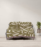 Nami Abstract Floral Blanket Throw in Olive Green and Beige, draped over a sofa