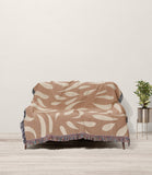 Nami Abstract Floral Blanket Throw in Rust and Beige, draped over a sofa