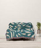 Nami Abstract Floral Blanket Throw in Teal and Beige, draped over a sofa