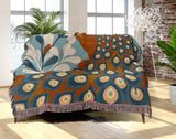 Nivo Peacock Cotton Blend Blanket Throw in Burnt Orange, draped over a chair