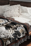 Piya Peacock Cotton Blend Blanket Throw in Black, on a bed