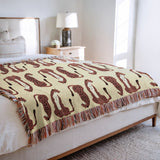 Ren Leopard Cotton Blend Blanket Throw in Orange and Burnt Orange, draped over a chair