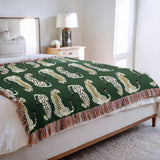 Ren Leopard Cotton Blend Blanket Throw in Green and Off-White, draped over a chair