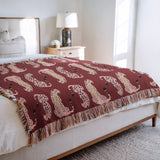 Ren Leopard Cotton Blend Blanket Throw in Red and Pink, draped over a chair