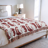 Ren Leopard Cotton Blend Blanket Throw in Red, Pink and Off-White, draped over a chair