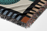 Sami Snake Cotton Blend Blanket Throw in Teal and Black, draped over a chair