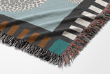 Sami Snake Cotton Blend Blanket Throw in Gray and Blue, draped over a chair