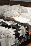 Shako Southwestern Cotton Blend Blanket Throw in Black, Gray and Off-White, draped over a chair