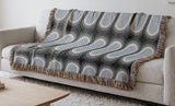 Speck Cotton Blend Blanket Throw in Blue, draped over a chair