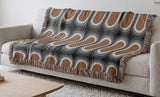 Speck Cotton Blend Blanket Throw in Burnt Orange, draped over a chair