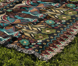 Tia Folksy Tiger Cotton Blend Blanket Throw in Black, Teal, Brown and Green, draped over a chair