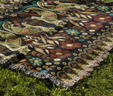 Tia Folksy Tiger Cotton Blend Blanket Throw in Black, Green, Red and Teal, draped over a chair