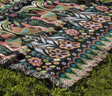 Tia Folksy Tiger Cotton Blend Blanket Throw in Black, Pink, Green and Teal, draped over a chair
