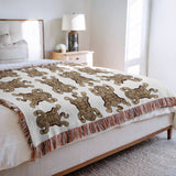 Usha Tibetan Tiger Cotton Blend Blanket Throw in Beige and Off-White, on a bed