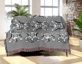 Usha Tibetan Tiger Cotton Blend Blanket Throw in Gray and Off-White, draped over a chair
