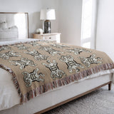Usha Tibetan Tiger Cotton Blend Blanket Throw in Soft Orange and Off-White, on a bed