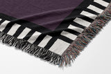 Vanjo Snake Cotton Blend Blanket Throw in Purple, Black and Off-White, draped over a chair