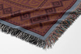 Voha Tibetan Tiger Cotton Blend Blanket Throw in Red, Blue and Burnt Orange, draped over a chair