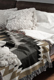 Zio Southwestern Cotton Blend Blanket Throw in Black, Gray, Dull Gold and Off-White, draped over a chair