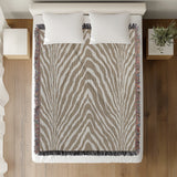 Zoe Animal Print Cotton Blend Blanket Throw in Beige, on a bed