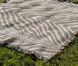 Zoe Animal Print Cotton Blend Blanket Throw in Beige, draped over a chair