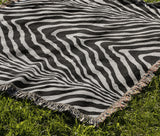 Zoe Animal Print Cotton Blend Blanket Throw in Black, draped over a chair