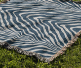 Zoe Animal Print Cotton Blend Blanket Throw in Blue, draped over a chair