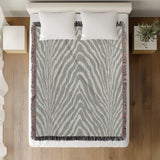 Zoe Animal Print Cotton Blend Blanket Throw in Gray, on a bed