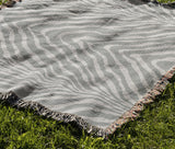 Zoe Animal Print Cotton Blend Blanket Throw in Gray, draped over a chair