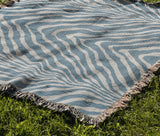 Zoe Animal Print Cotton Blend Blanket Throw in Light Blue, draped over a chair