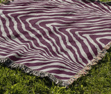 Zoe Animal Print Cotton Blend Blanket Throw in Purple, draped over a chair