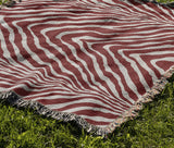 Zoe Animal Print Cotton Blend Blanket Throw in Red, draped over a chair