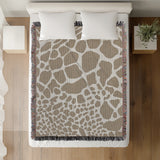 Zuma Animal Print Cotton Blend Blanket Throw in Beige, on a bed