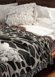 Zuma Animal Print Cotton Blend Blanket Throw in Black, draped over a chair