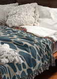 Zuma Animal Print Cotton Blend Blanket Throw in Blue, draped over a chair